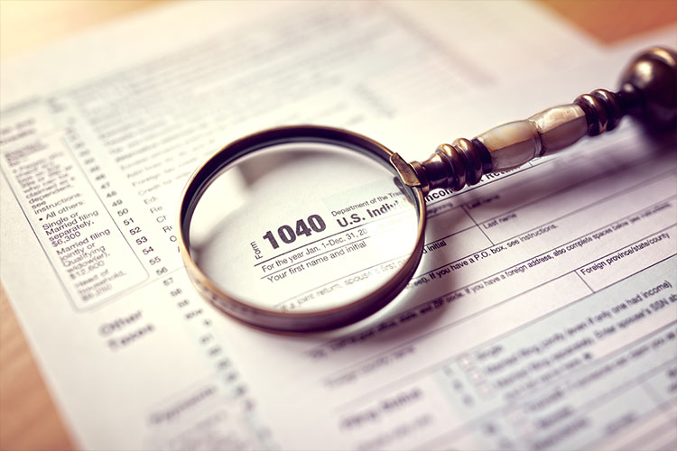 Agriculture-related tax matters: magnifying glass set on top of a 1040 tax form.